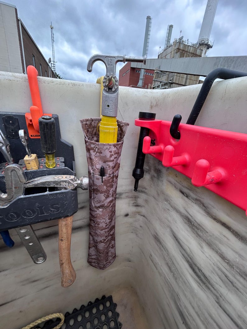 Pu&ograve; includere: Una collezione di strumenti e attrezzature, tra cui un martello, chiavi inglesi e uno strumento giallo e argento, sono conservati in un contenitore bianco. &Egrave; visibile anche un rack rosso con ganci. Gli strumenti sono organizzati per un facile accesso.