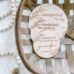 Peut inclure: Trois cercles en bois avec le texte "handpicked for earth by" sur le cercle du haut, "handpicked for earth by my grandpa" sur le cercle du bas et "handpicked by my" sur le cercle du milieu. Les cercles sont dans un panier en bois.