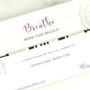 May include: A black and white beaded bracelet with a black string. The bracelet spells out "breathe" in Morse code. The card reads "Breathe Morse Code Bracelet" and includes the Morse code for "breathe".