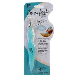 May include: A turquoise blue craft knife with a comfortable grip and a storage compartment for extra blades. The packaging includes the text "Comfort Craft Tools by: Ingvild Bolme" and "Includes 4 distinct blades Craft Knife".