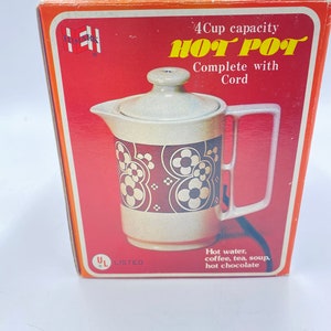 May include: Vintage "Hot Pot" electric water heater in its original box. The box is red with the words "Hot Pot" in yellow. The pot is beige with a floral design and a handle. It is designed to heat water, coffee, tea, soup, and hot chocolate.