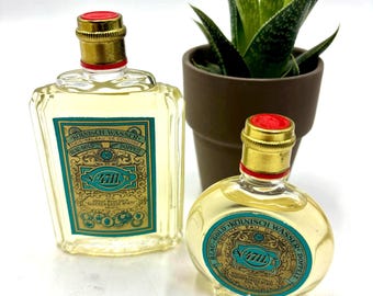 May include: Two vintage cologne bottles with gold accents and red stoppers. The bottles have a teal and gold label with the text "4711". A small potted aloe vera plant is in the background.