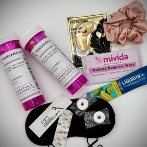 Pu&ograve; includere: Una collezione di articoli per il recupero post sbornia, tra cui due bottiglie rosa e bianche etichettate, una maschera per gli occhi dorata, un elastico per capelli rosa, salviette struccanti, una bustina di moltiplicatore di idratazione, mentine, una mascherina per dormire e stuzzicadenti.