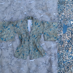 Puede incluir: Un kimono azul y blanco con un diseño geométrico. El kimono está abierto por delante y tiene mangas largas.