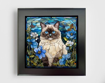 May include: A square wall art piece in a black frame featuring a stained glass style illustration of a Siamese cat with bright blue eyes, surrounded by blue flowers and two orange butterflies against a swirling blue and white background.