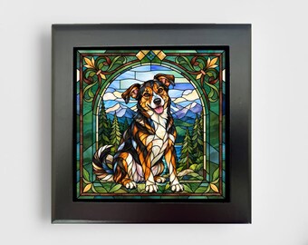 May include: A square black frame containing a stained glass style art piece depicting a tricolor dog sitting in front of a mountain and forest landscape. The dog has black, brown, and white fur, and the background features blue sky and green trees.