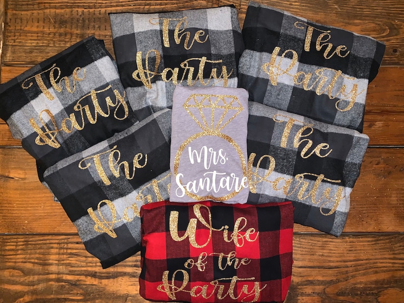 May include: A set of six flannel shirts with black and white plaid patterns. The shirts have gold glitter lettering that says "The Party". There is also a gray shirt with a gold glitter diamond ring and the text "Mrs. Santare". A red and black plaid shirt with gold glitter lettering that says "Wife of the Party".