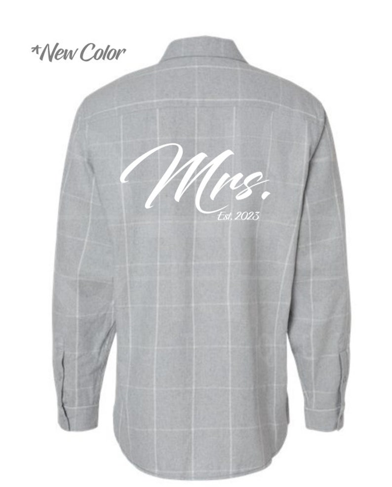 May include: A gray plaid long-sleeve button-down shirt with the word "Mrs." and "Est. 2023" printed on the back in white.