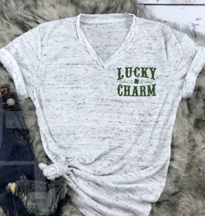 May include: White t-shirt with a green shamrock and the text "LUCKY CHARM" printed on the front.