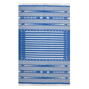 May include: A rectangular blue and white patterned rug with a fringe on the top and bottom edges. The rug features horizontal white stripes and decorative white geometric shapes. The rug is designed for indoor or outdoor use.