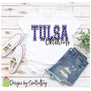 Puede incluir: Camiseta blanca con un diseño de lunares azules y blancos que dice "TULSA Oklahoma" en texto negro.