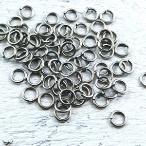 May include: A large pile of silver jump rings, a type of metal ring used in jewelry making.