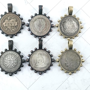 May include: Six antique-style coin pendants with various designs, including a sun, Buddha, and an Indian head. Each pendant has a decorative border and a loop for a chain. The pendants are in shades of silver and bronze.