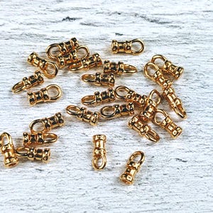 May include: A collection of gold-toned metal jewelry findings, including barrel clasps and jump rings. These findings are ideal for creating necklaces, bracelets, and other jewelry pieces.