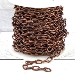 May include: A spool of copper chain, wound tightly. The chain is a simple oval link style. The chain is a warm copper color.