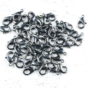 May include: A pile of black metal lobster clasps, a type of fastener used for jewelry making.