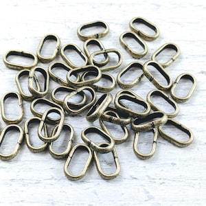 May include: A pile of antique gold oval jump rings, a type of metal hardware used in jewelry making.