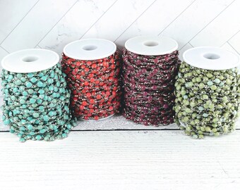 May include: Four spools of chain with beads, each spool is a different color: turquoise, red, purple, and green.
