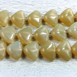 May include: A strand of iridescent, light brown triangle-shaped beads. The beads are strung on a clear thread.