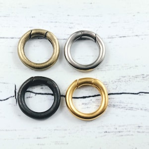 May include: Four metal key rings in different finishes: antique brass, black, silver, and gold.