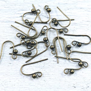 May include: A group of 12 antique gold earring hooks with small round balls at the end of each hook.
