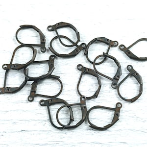 May include: A collection of antique bronze-colored leverback earring findings. These jewelry components feature a hinged design with a curved lever and a small loop for attaching earrings. Ideal for DIY jewelry making.