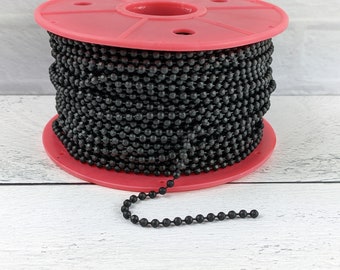 May include: A spool of black chain with round links. The chain is wound around a pink plastic spool.