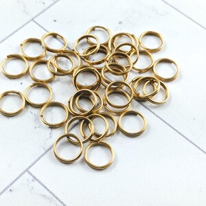 May include: A pile of gold jump rings, a type of metal ring used in jewelry making.