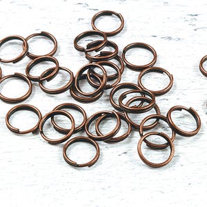 Puede incluir: Un montón de anillos de salto de cobre, un tipo de anillo de metal utilizado en la fabricación de joyas.