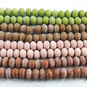 May include: Four rows of wooden beads in various colours, including green, brown, pink, and brown. The beads are all round and have a frosted finish.