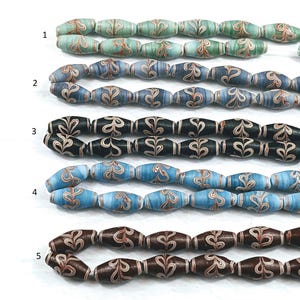 May include: Five strands of glass beads with a swirling pattern. The beads are in shades of blue, green, brown, and black. Each strand has a number next to it.
