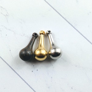 May include: Three teardrop-shaped metal charms in gold, silver, and black.