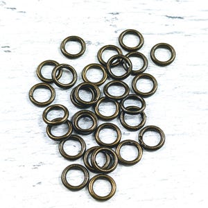 May include: A pile of antique gold jump rings, a type of metal ring used in jewelry making.
