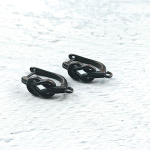 May include: A pair of black metal earring findings with a knot design. The findings are in the shape of a loop with a small hook on the side.
