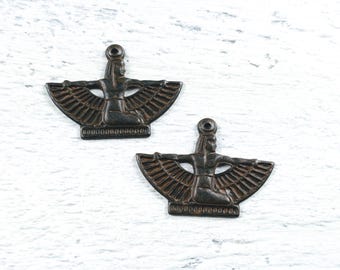 May include: Two antique bronze charms featuring a winged goddess figure with outstretched arms. The charms have a detailed design and a textured finish.