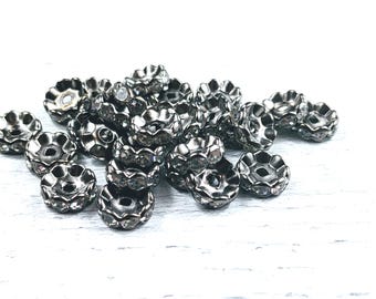 May include: A pile of silver-toned metal embellishments with clear rhinestones. Each embellishment has a scalloped edge and a center hole.