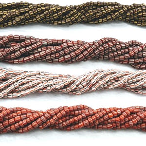 May include: Four strands of glass beads, each with a different colour pattern. The top strand is brown and gold, the second strand is red and white, the third strand is white and red, and the bottom strand is orange and red.