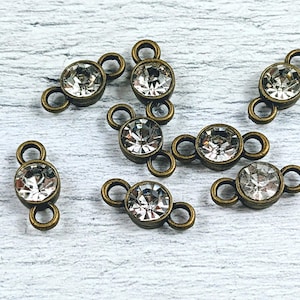 May include: Eight antique bronze connector charms with clear crystal rhinestones. Each charm has two loops for attaching jewelry.