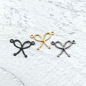 May include: Three metal bow charms in gold, black and silver. Each charm has a loop on either side for attaching to jewellery or other crafts.