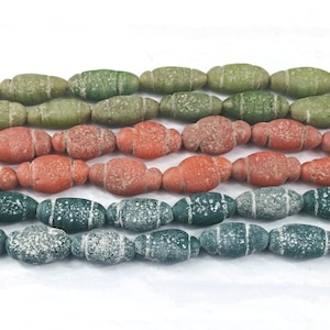 May include: A strand of oval-shaped beads with a speckled, textured surface. The beads are in three colors: green, orange, and dark green.