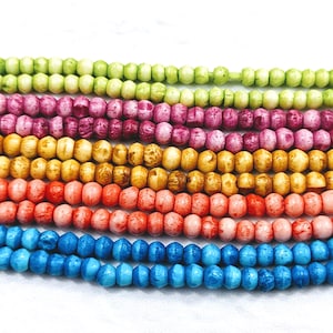 May include: A close-up of a strand of colourful wooden beads. The beads are arranged in rows, with each row a different colour. The colours are green, pink, yellow, orange, and blue.