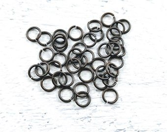 May include: A pile of small, round, bronze jump rings. The rings are all the same size and are arranged in a random pattern.