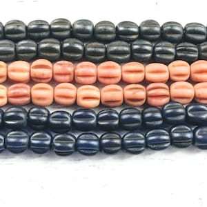 Puede incluir: Filas de cuentas vintage en tonos negro, coral y azul marino. Las cuentas tienen una forma acanalada, similar a un barril, creando una apariencia texturizada. Ideales para la creación de joyas y proyectos de artesanía.