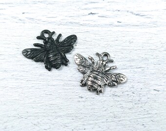 May include: Two bee charms, one black and one silver, with detailed wings and bodies. The charms are perfect for adding a touch of nature to jewelry or crafts.