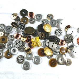 May include: A collection of assorted buttons in various shapes, sizes, and finishes, including metallic silver, bronze, gold, and copper tones. The assortment features intricate filigree patterns, smooth surfaces, and a single yellow bee-shaped button.