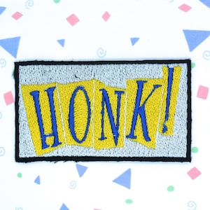 May include: A yellow and blue embroidered patch with the word "HONK!" in a stylized font.