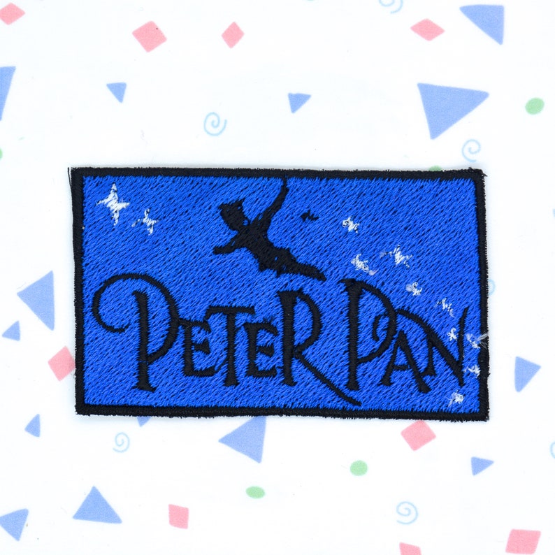 May include: A blue embroidered patch with a silhouette of Peter Pan flying with stars and the text "PETER PAN" in black.