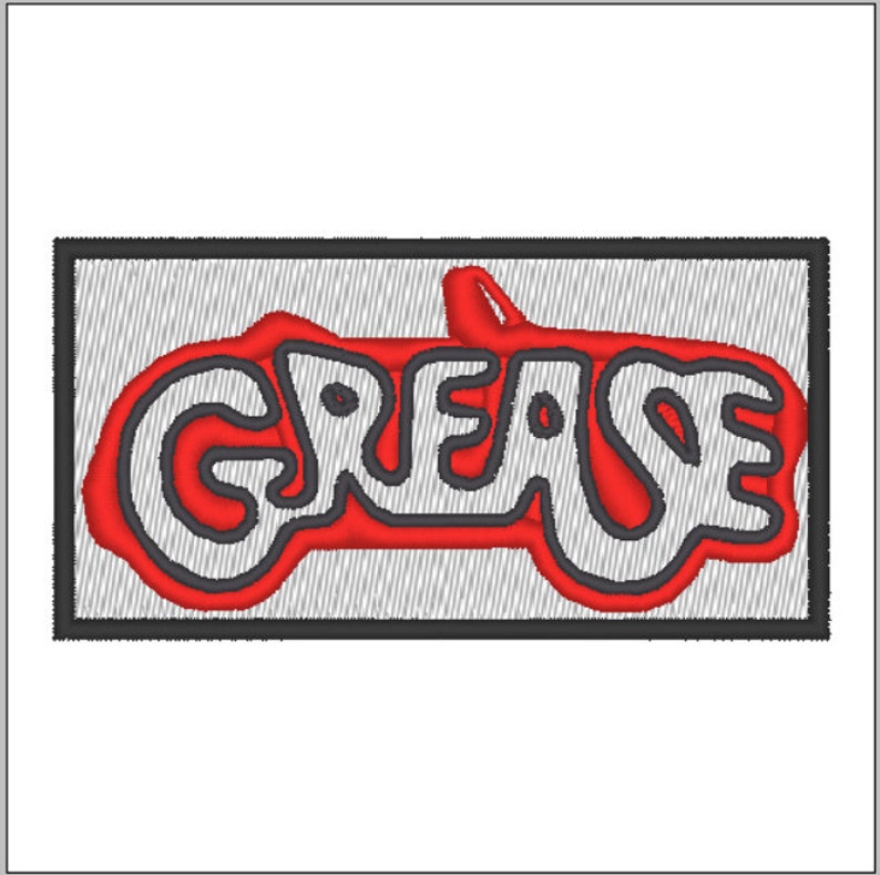 Peut inclure: Un patch brod&eacute; rouge et blanc avec le mot "GREASE" dans une police de caract&egrave;res stylis&eacute;e. Le mot est soulign&eacute; en noir et l'arri&egrave;re-plan est gris.