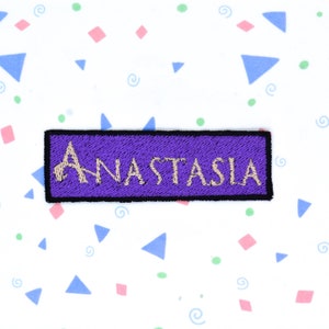 May include: Purple embroidered patch with the word "ANASTASIA" in gold thread.