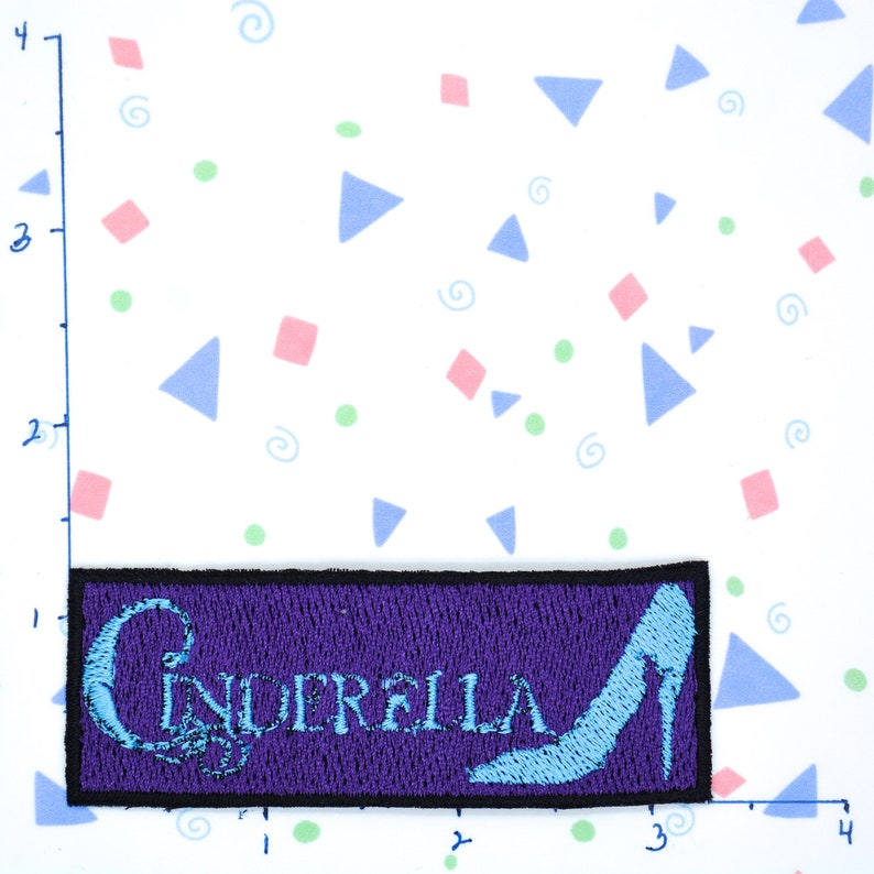 May include: Purple embroidered patch with the word "Cinderella" in blue lettering and a blue glass slipper.